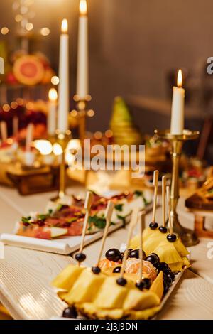 Mahlzeit. Festlicher Buffettisch für Gäste. Auswahl an Aufschnitt, Häppchen auf Holzspießen, festliche Snacks mit Obst und Salaten. Empfang im Teil Stockfoto