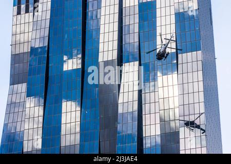 Wien, Helikopter vor dem Wolkenkratzer DC Tower 1, Spiegelglasfassade, dunkle Fenster, Airbus Helicopters AS355 Ecureuil, für Dreharbeiten zum Netflix-Film 'Tyler Rake ñ Extraction' mit dem Schauspieler Chris Hemsworth im Bezirk 22. Donaustadt, Österreich Stockfoto