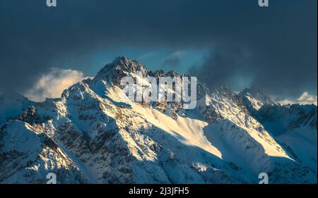 Wilde Berglandschaft im Winter. Sonne und Wolken an der verschneiten Großen Schlenkerspitze. Lechtaler Alpen, Tirol, Österreich, Europa Stockfoto