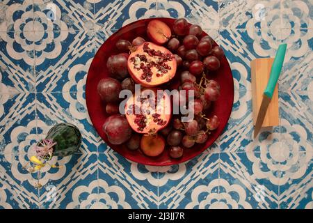 Stillleben rohe Pflaumen, Granatapfel und Trauben im Vintage-Hintergrund Stockfoto