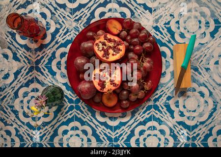 Stillleben rohe Pflaumen, Granatapfel und Trauben im Vintage-Hintergrund Stockfoto