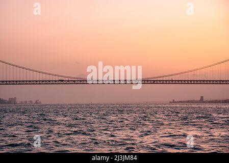 Die 25 de Abril Brücke supinsion Brücke von Lissabon bei Sonnenuntergang. Wunderschöne rote und türkisfarbene Farben über dem Fluss Tejo Stockfoto