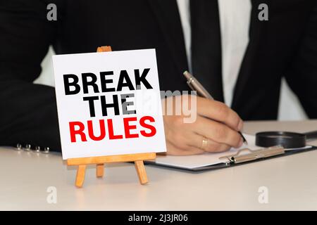 Closeup Geschäftsfrau Hände halten weiße Karte Schild mit Bruch die Regeln Textnachricht auf graue Wand Büro Hintergrund isoliert. Retro-Instagram Stil ich Stockfoto