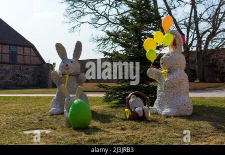 Osterhasen sitzen auf grünem Rasen und halten Ballons. Stockfoto