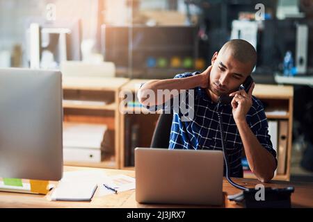 Das hört sich überhaupt nicht gut an Eine kurze Aufnahme eines jungen Designers, der gestresst aussagt, während er in einem Büro am Telefon telefoniert. Stockfoto