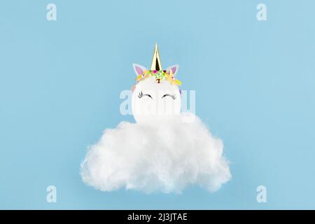 Ostereinhorn-Ei fliegt auf blauem Hintergrund. Frohe ostern Banner. Inspiration für Aktivitäten für Kinder. Grußkarte oder Poster. Platz für Text kopieren. Levitation Stockfoto