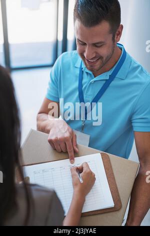 Ich brauche nur einige Ihrer Angaben hier. Eine Aufnahme einer Geschäftsfrau, die ein Paket unterschrieb, das von einem Kurier an ihr Büro geliefert wurde. Stockfoto