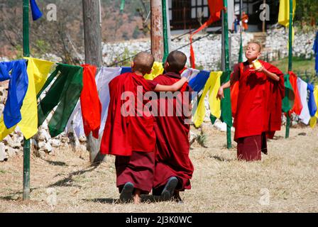 Zwei junge Mönche gehen während des bhutanischen Paro Tshechu Festivals in Paro Dzong, einem Kloster und einer Festung in Paro, Bhutan, und Paro, Bhutan, zusammen Stockfoto