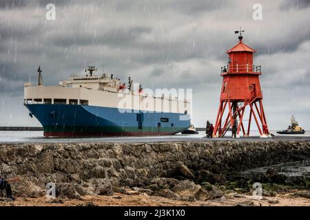 Frachtschiff und Herde am Leuchtturm von Groyne auf dem Pier in South Shields während eines Regenfalls; South Shields, Tyne und Wear, England Stockfoto