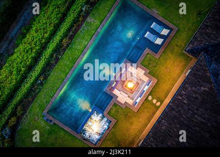 Blick auf die Drohne direkt über einem Swimmingpool, auf dem Dach des Gebäudes und üppiger Vegetation auf einem Grundstück auf Maui, Hawaii, USA Stockfoto