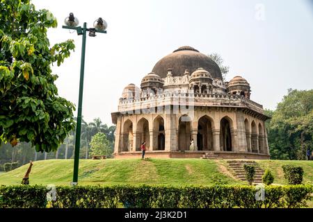 Traditionelle indische Architektur eines hinduistischen Tempels im Lohdi Park, mit einem Mann, der eine Frau fotografiert; Dehli, Indien Stockfoto