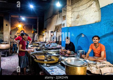 Junge Männer, die in einer kommerziellen Küche in Indien arbeiten und Essen unter Licht zubereiten; Amritsar, Punjab, Indien Stockfoto