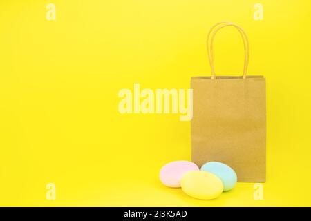 Papiertüte auf gelbem Hintergrund und ostereier. Speicherplatz kopieren Stockfoto