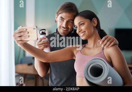 Statusaktualisierung – Training abgeschlossen. Eine kurze Aufnahme eines sportlichen jungen Paares, das Selfies macht, bevor es zu Hause mit dem Training beginnt. Stockfoto