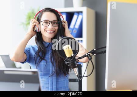 Schöne Frau in Kopfhörern vor dem Mikrofon im Studio Stockfoto