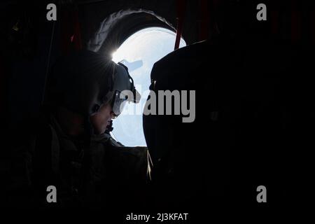 Ein Leiter der Hubschrauber-Crew der Alaska Army National Guard CH-47 Chinook wird der B Company, 2-211. General Support Aviation Bataillon, zugewiesen und sucht nach der Geronimo Drop Zone auf der Joint Base Elmendorf-Richardson, Alaska, 7. April 2022. Die 2-211 GSAB unterstützte einen Hubschraubersprung für die US Air Force Detachment 1, 3. Air Support Operations Squadron in der Geronimo Drop Zone, wodurch das Training der totalen Kräfte maximiert wurde, um die kurzfristige Einsatzbereitschaft in einer arktischen Umgebung zu demonstrieren. (USA Luftwaffe Foto von Senior Airman Emily Farnsworth) Stockfoto