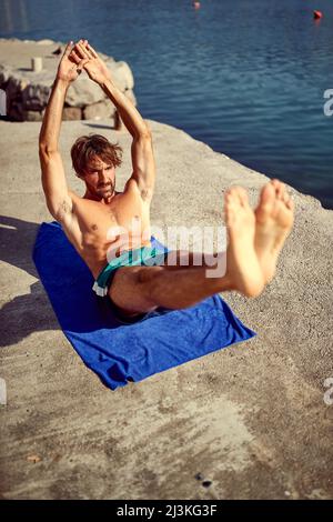 Mann übt am See.der junge Mann praktiziert Yoga am Bergsee. Stockfoto