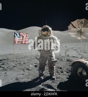 Apollo 17 Astronaut Eugene Cernan auf dem Mond mit der amerikanischen Flagge und der schirmförmigen High-Gain-Antenne ihres Mondrovers. Sie befinden sich im Taurus-Littrow-Tal mit den Sculptured Hills im Hintergrund. Stockfoto