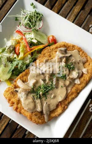 deutsches Kalbfleisch Jagerschnitzel Schnitzel mit Pilzsauce und Salat Stockfoto