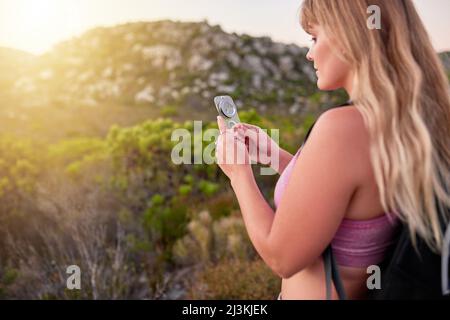 Prüfen, ob Shes auf der richtigen Route sind. Aufnahme einer attraktiven jungen Frau, die während einer Wanderung einen Kompass liest. Stockfoto