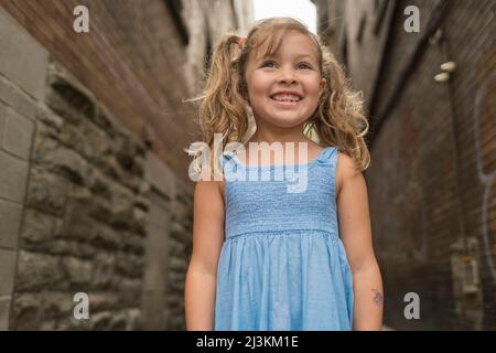 Außenportrait eines jungen Mädchens, das in einer Gasse steht; Toronto, Ontario, Kanada Stockfoto