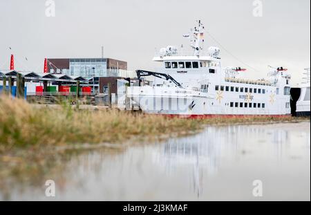 Harlesiel, Deutschland. 07. April 2022. Die Deutsche Bahn Fähre Wangerooge liegt an einer Kaimauer im Hafen. Nachdem die Fähre am 31. März 2022 am Hafeneingang der Nordseeinsel Wangerooge auf Grund gelaufen ist, müssen sich Inselbewohner und Osterurlauber auf Änderungen im Fahrplan von und zur ostfriesischen Insel vorbereiten. Quelle: Hauke-Christian Dittrich/dpa/Alamy Live News Stockfoto