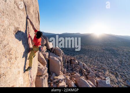 Ein Bergsteiger, der sich eine technische Granitwand hocharbeitet. Stockfoto