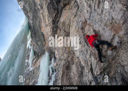 Ein Bergsteiger trocken Werkzeuge eine Felswand mit Eispickel und Steigeisen im Osten Vail Amphitheater in Colorado. Stockfoto