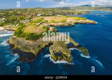 Nahaufnahme, Luftaufnahme von Devil's Träne und der felsigen Küste von Nusa Lembongan mit dem türkisfarbenen Wasser des Bali Meeres, das gegen das Ufer stürzt Stockfoto