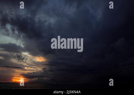 Dunkle und bedrohliche Sturmwolken bilden sich am Himmel über dem Ozean bei Sonnenuntergang; Gili Trawangan, Lombok, West Nusa Tenggara, Indonesien Stockfoto