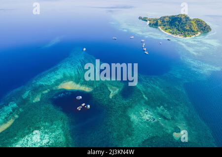 Luftaufnahme von Booten, die um die Meeresgewässer rund um eine Insel und eine Küstenlagune im Komodo National Park fahren Stockfoto