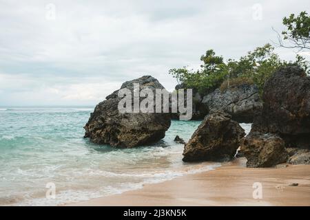 Große Felsformationen am Strand entlang der Halbinsel Bukit am Uluwatu Beach, mit Blick auf den Indischen Ozean in Süd-Bali an einem bewölkten Tag Stockfoto