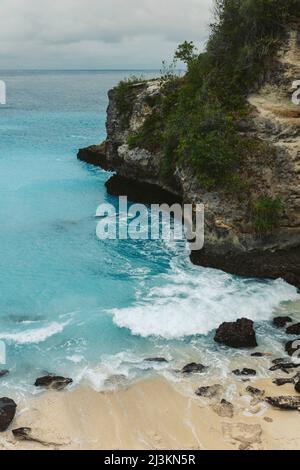 Die felsige Küste und der Strand des Resorts Lembongan am Rande des türkisfarbenen Wassers vor der Küste von Bali Stockfoto