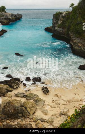 Die felsige Küste und der Strand des Resorts Lembongan am Rande des türkisfarbenen Wassers vor der Küste von Bali Stockfoto