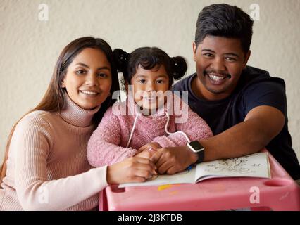 Das sind wertvolle Momente mit unserer Tochter. Aufnahme einer jungen Eltern, die ihrem kleinen Mädchen dabei helfen, ein Malbuch zu vervollständigen. Stockfoto