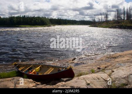 Ein Kanu an einer felsigen Küste.; Winisk River, Ontario, Kanada. Stockfoto
