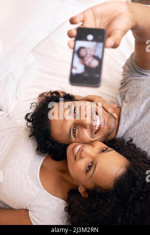 Erfassen eines Speichers. Ein nettes Paar, das ein Selfie auf dem Bett gemacht hat. Stockfoto