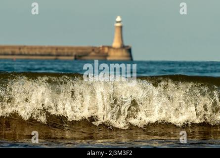 Wellengang am Strand im Vordergrund mit Tynemouth North Pier Licht und Pier im Hintergrund; South Shields, Tyne and Wear, England Stockfoto