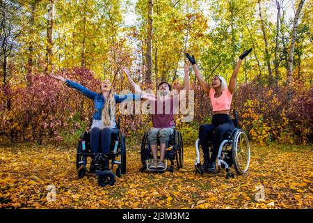 Eine Gruppe von drei jungen Querschnittsgelähmten in einem Park an einem schönen Herbsttag; Edmonton, Alberta, Kanada Stockfoto