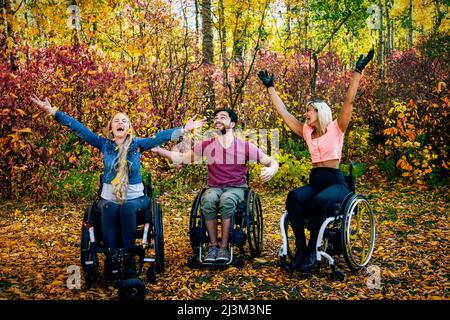 Eine Gruppe von drei jungen Querschnittsgelähmten in einem Park an einem schönen Herbsttag; Edmonton, Alberta, Kanada Stockfoto