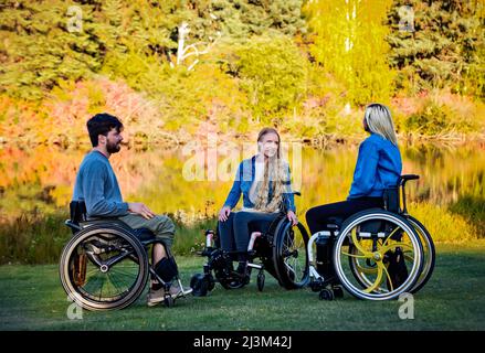 Eine Gruppe von drei jungen Querschnittsgelähmten, die an einem schönen Herbsttag gemeinsam in einem Park in Edmonton, Alberta, Kanada, unterwegs waren Stockfoto