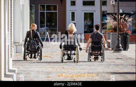 Drei junge querschnittsgelähmte Freunde verbringen Zeit miteinander, um einen Gehweg außerhalb eines Stadtgebiets zu befahren; Edmonton, Alberta, Kanada Stockfoto