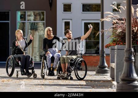 Drei junge querschnittsgelähmte Freunde verbringen Zeit miteinander beim Einkaufen und machen ein Selbstporträt draußen in einem Stadtgebiet; Edmonton, Alberta, Kanada Stockfoto