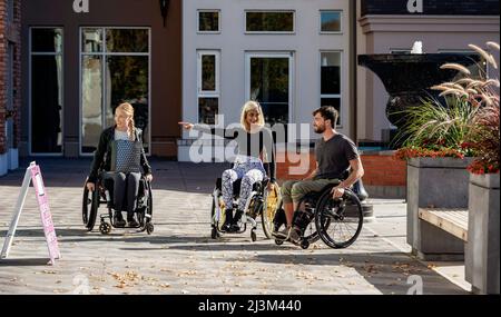 Drei junge querschnittsgelähmte Freunde, die gemeinsam in einem Stadtgebiet einkaufen, Edmonton, Alberta, Kanada Stockfoto