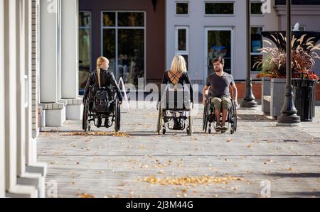 Drei junge querschnittsgelähmte Freunde verbringen Zeit miteinander, um einen Gehweg außerhalb eines Stadtgebiets zu befahren; Edmonton, Alberta, Kanada Stockfoto