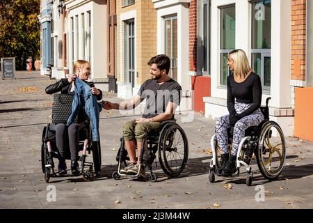 Drei junge querschnittsgelähmte Freunde, die gemeinsam in einem Stadtgebiet einkaufen, Edmonton, Alberta, Kanada Stockfoto