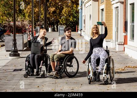 Drei junge querschnittsgelähmte Freunde, die in einem Stadtgebiet Zeit miteinander verbringen, um draußen zu shoppen und Fotos zu machen; Edmonton, Alberta, Kanada Stockfoto