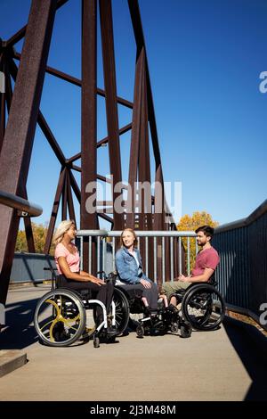 Eine Gruppe von drei jungen Querschnittsgelähmten, die an einem schönen Herbsttag gemeinsam in einem Park in Edmonton, Alberta, Kanada, unterwegs waren Stockfoto