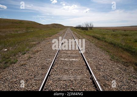 Bahngleise auf einer weiten Landschaft der kanadischen Prärien, die in die Ferne führen; Sanctuary, Saskatchewan, Kanada Stockfoto