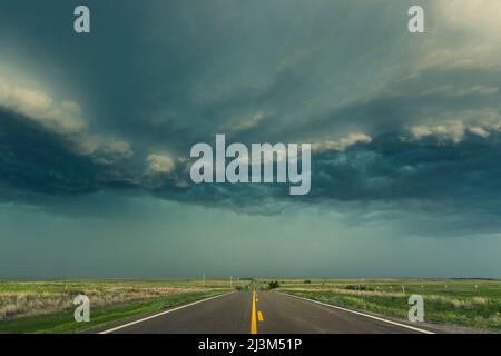 In der Tornado Alley, Kansas, USA, ragt während der Sturmsaison eine Regenmauer aus einem Gewitterkomplex auf die Autobahn Stockfoto